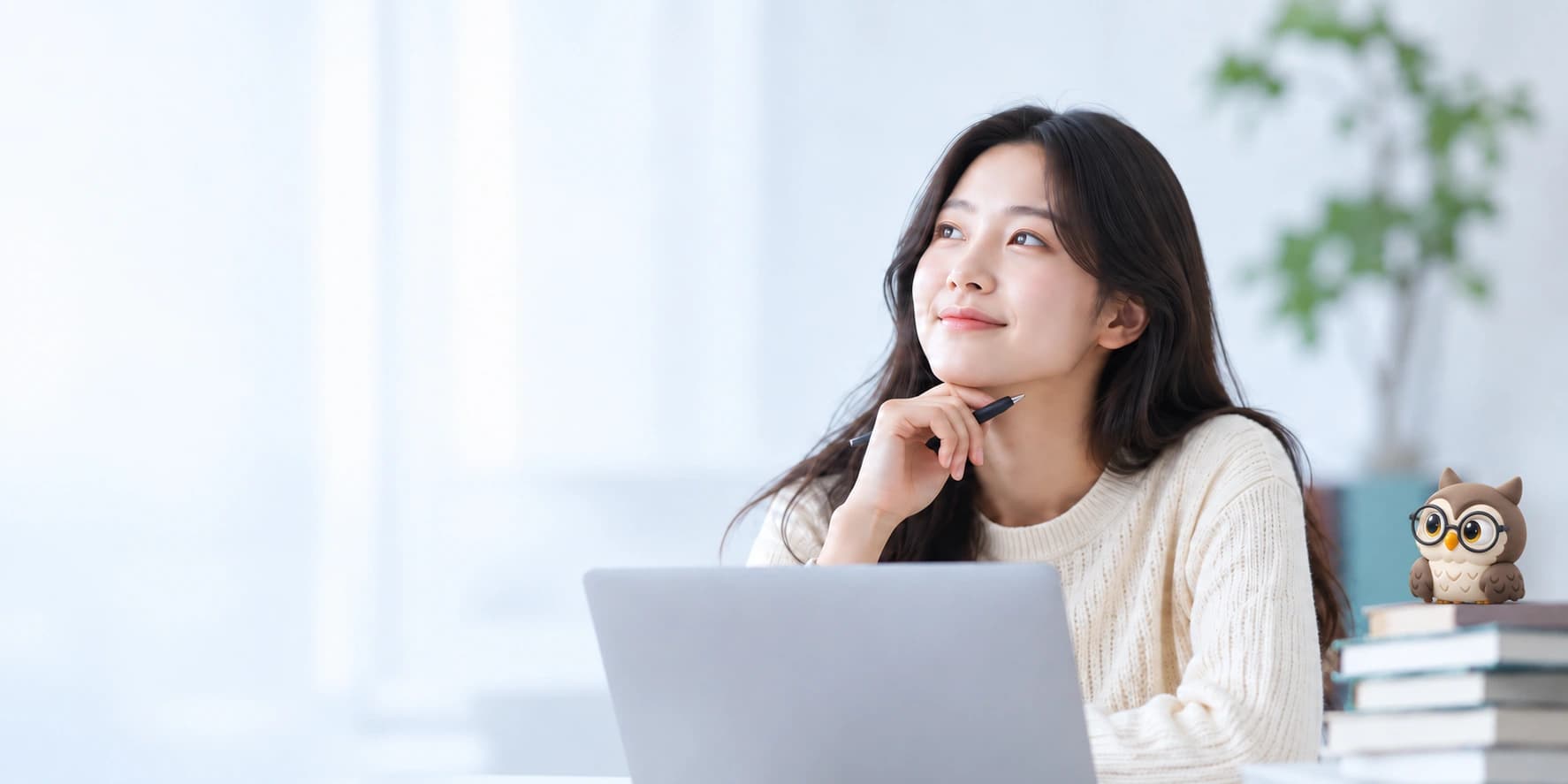 노트북 앞에서 펜을 들고 생각하는 학습자. 책 위에는 작은 안경 올빼미가 함께 있습니다.